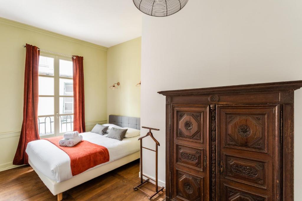 a bedroom with a bed and a wooden dresser at Dame de Coeur - Appartement spacieux en plein centre historique in Rennes