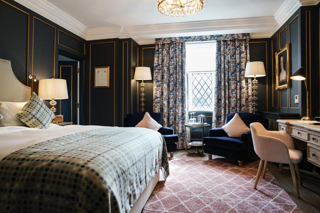 a bedroom with a bed and a desk and a window at The White Hart Hotel in Kingston upon Thames