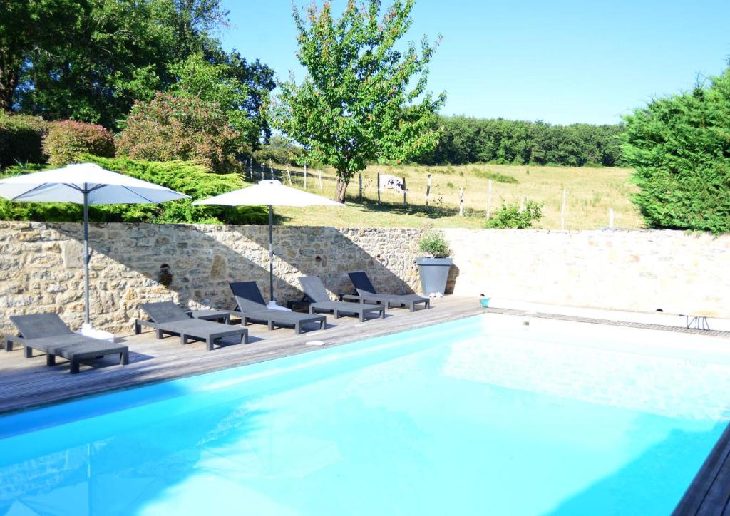 a swimming pool with lounge chairs and umbrellas at Chambre d'hôtes A la clé des champs Varen in Varen