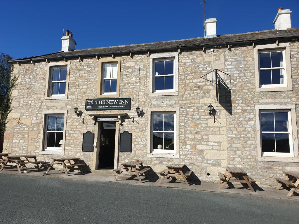 un edificio de piedra con mesas de picnic delante de él en The New Inn, en Skipton