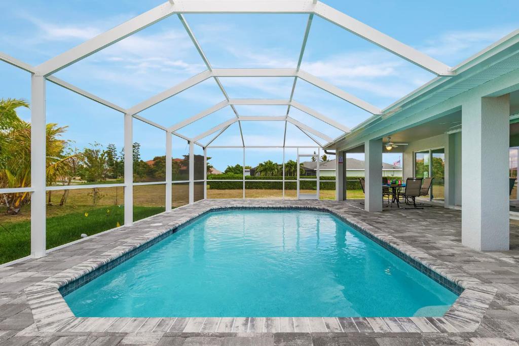 een zwembad met een glazen dak boven een huis bij Newly built home with heated pool, close to many amenities - Villa Sandle in Cape Coral