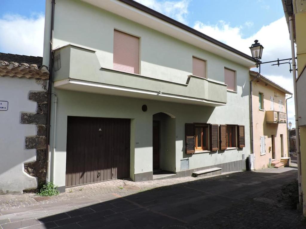 una casa blanca con una puerta y un garaje en CASA FIGUS Via Roma 20 Narbolia, en Narbolia