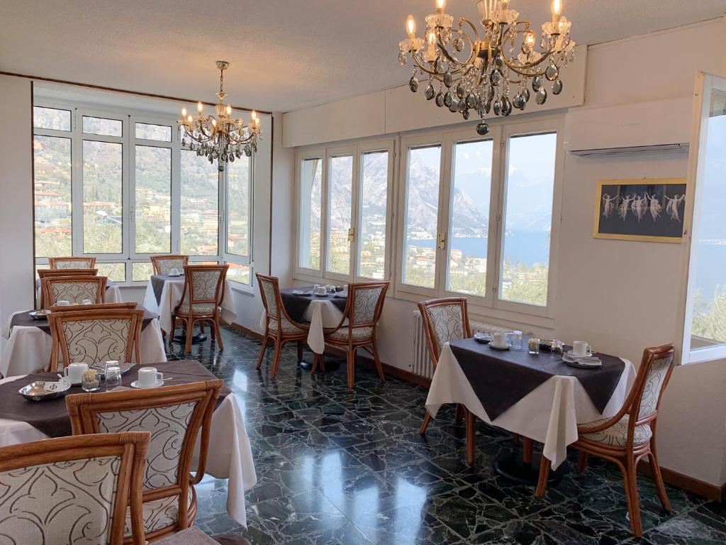 a dining room with tables and chairs and windows at Hotel Villa Margherita in Limone sul Garda