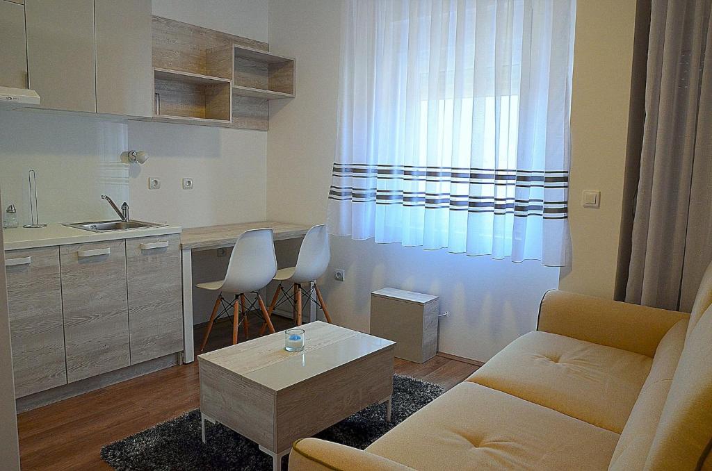sala de estar con sofá, mesa y cocina en Lux Apartmani, en Kladovo