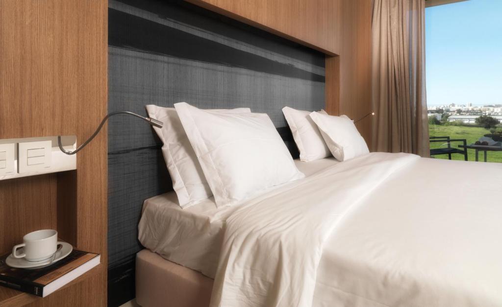 a bedroom with a large white bed with a window at Agua Hotels Riverside in Ferragudo