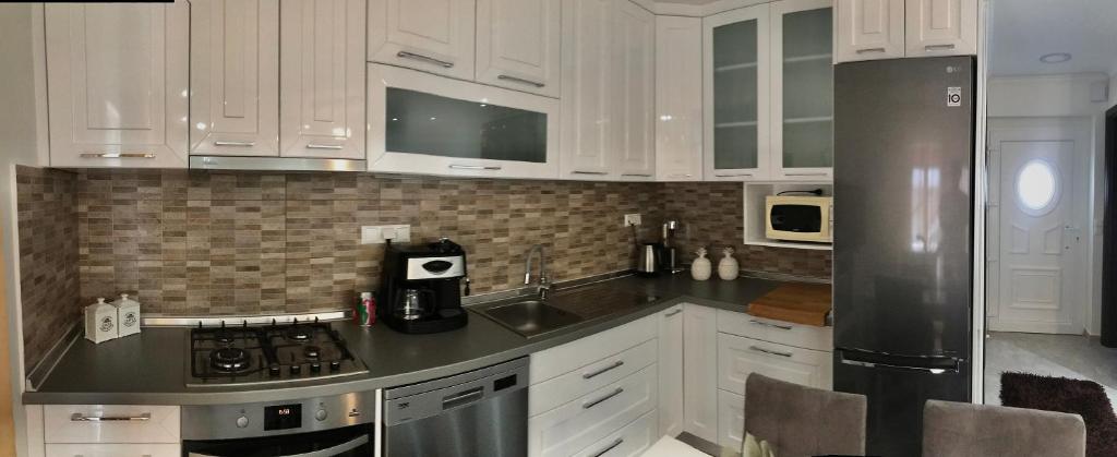 a kitchen with white cabinets and a stainless steel refrigerator at Nikos Apartament in Prinos
