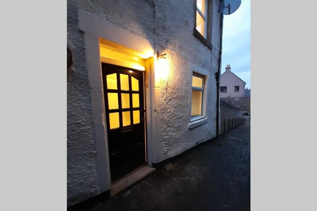 a door to a building with a light on it at The Snug, a great flat in the heart of Peebles. in Peebles