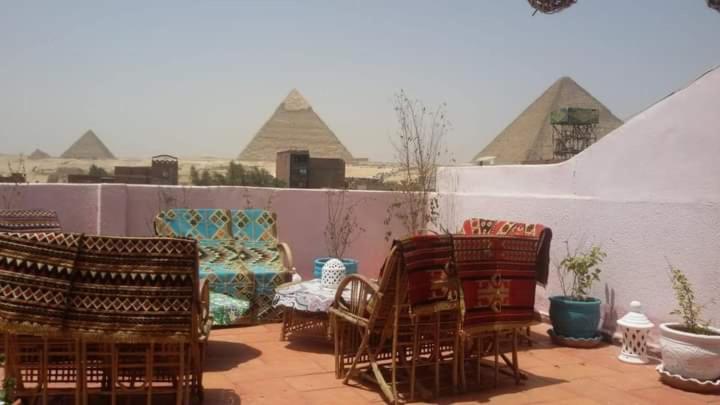 a group of chairs sitting on a patio with pyramids at Ra Guest house in Cairo