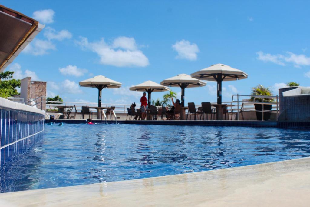 a swimming pool with umbrellas and tables and chairs at Pipas Bay in Pipa