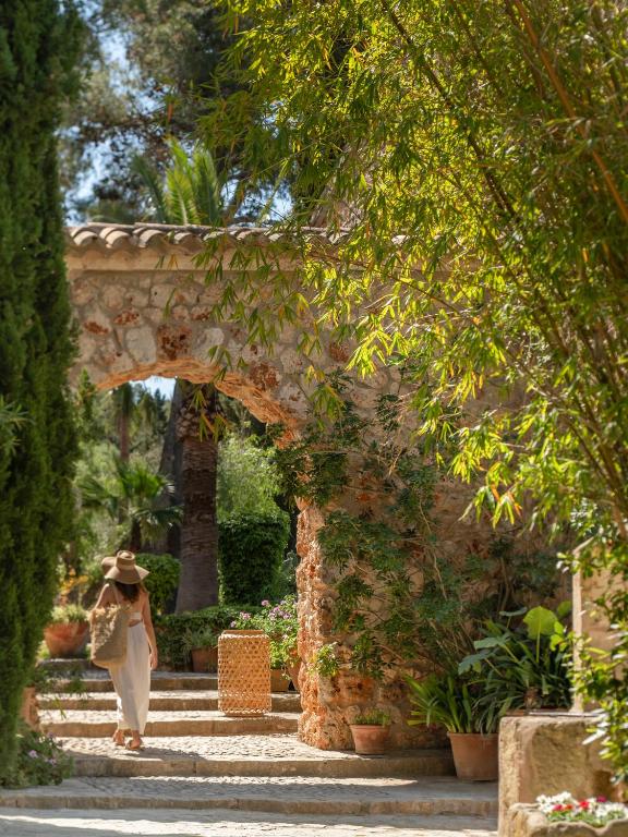 a woman walking through an archway in a garden at Agroturismo Son Fogueró - Adults Only in Maria de la Salut