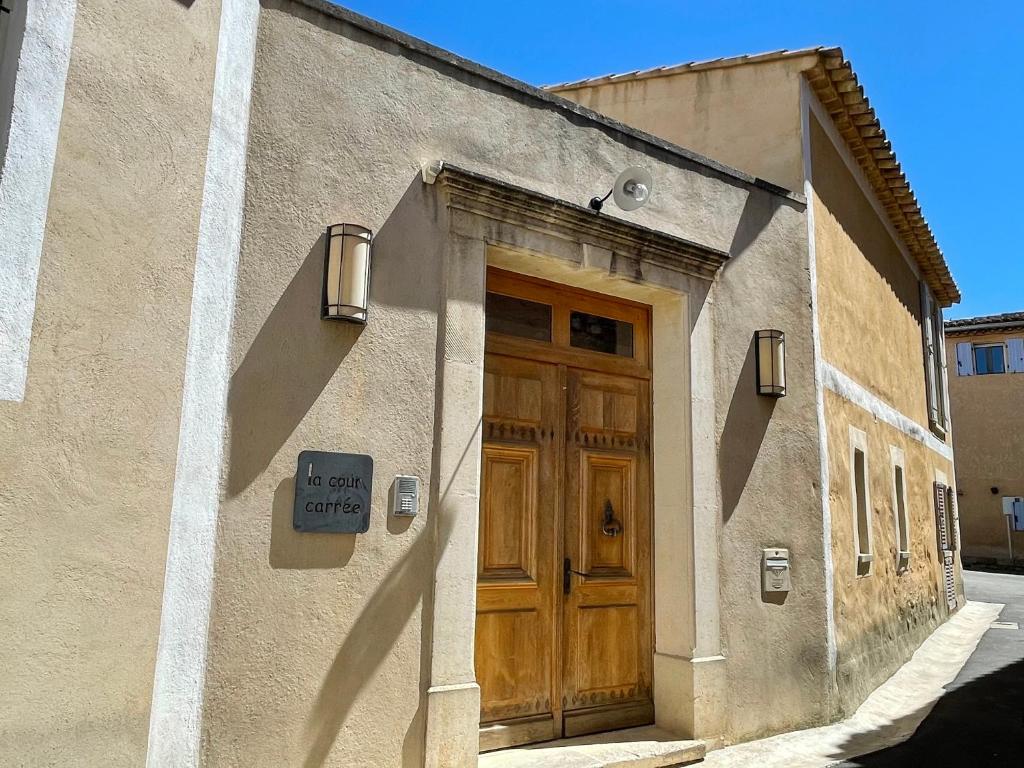 un bâtiment avec une porte en bois et un panneau. dans l'établissement La Cour Carrée, à Rustrel