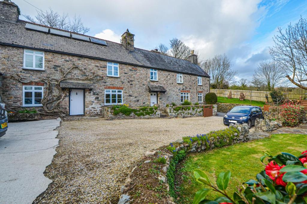 a stone house with a driveway and a car parked in front at The Annex at Middle Filham in Ivybridge