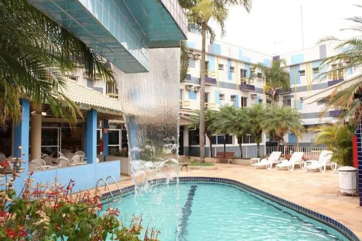 uma piscina com uma fonte em frente a um edifício em Trade Garden Hotel em Araras
