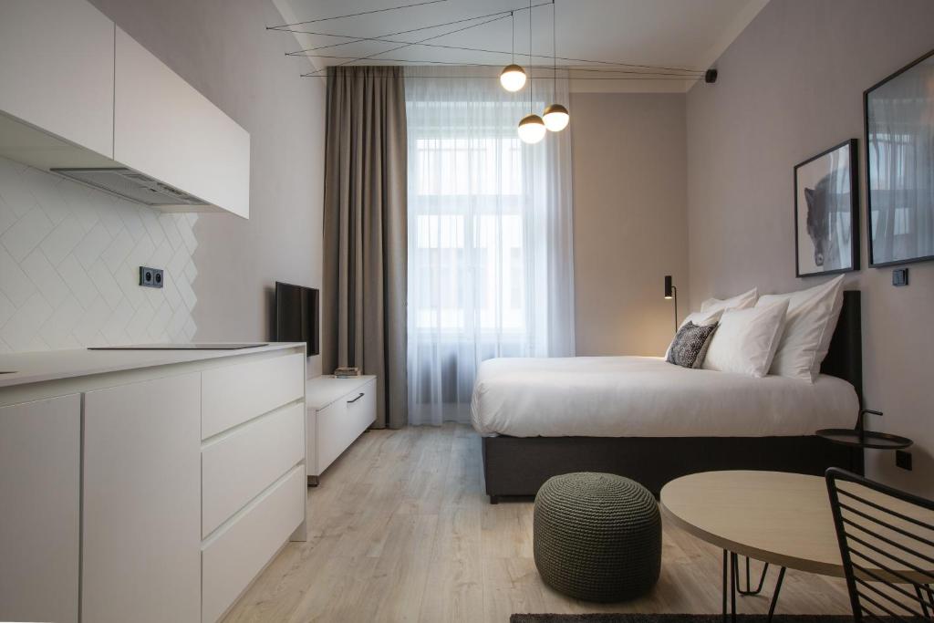 a bedroom with a bed and a table and a kitchen at OREA Place Seno in Prague