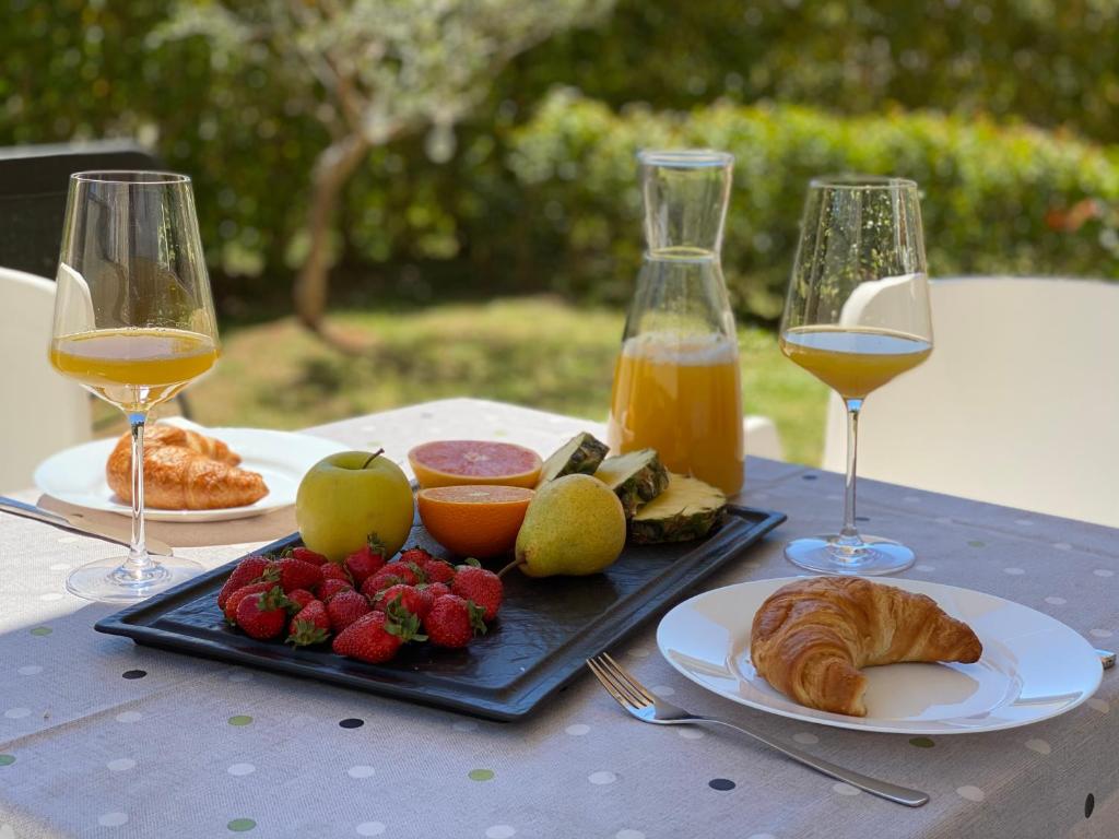 a table with two glasses of wine and a plate of food at Apartment Punta Premantura E with garden in Premantura