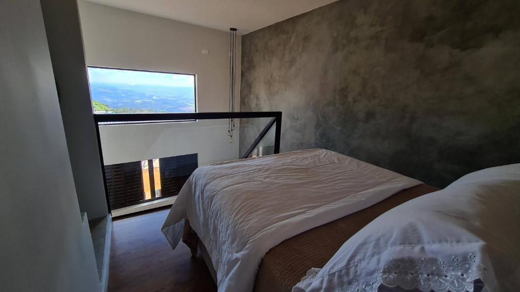 a bedroom with a bed and a large window at Pousada das Estrelas in São Thomé das Letras