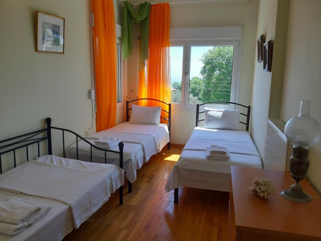 a room with two beds and a table and a window at Palio Villa in Paleo Tsifliki