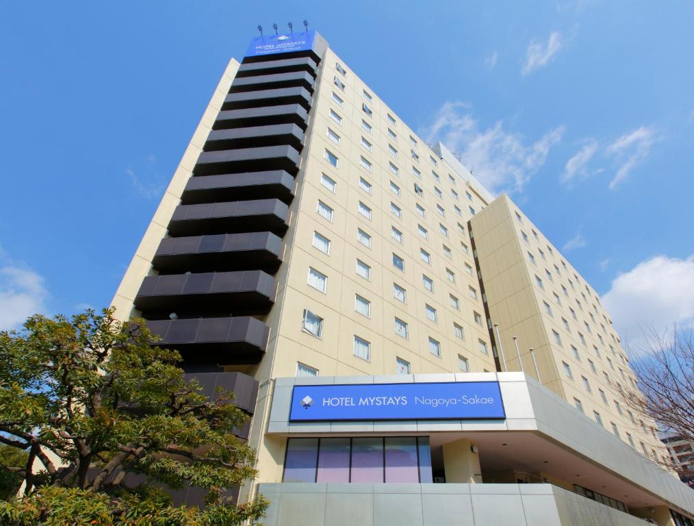 Un alto edificio bianco con un cartello blu sopra di HOTEL MYSTAYS Nagoya Sakae a Nagoya