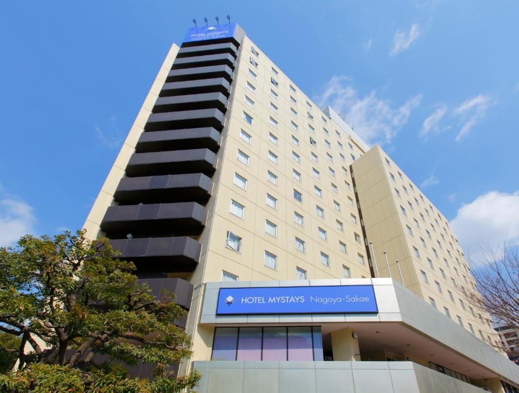 a tall white building with a blue sign on it at HOTEL MYSTAYS Nagoya Sakae in Nagoya