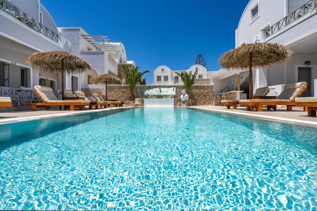 a swimming pool with chaise lounge chairs in a resort at Kalya Suites in Kamari