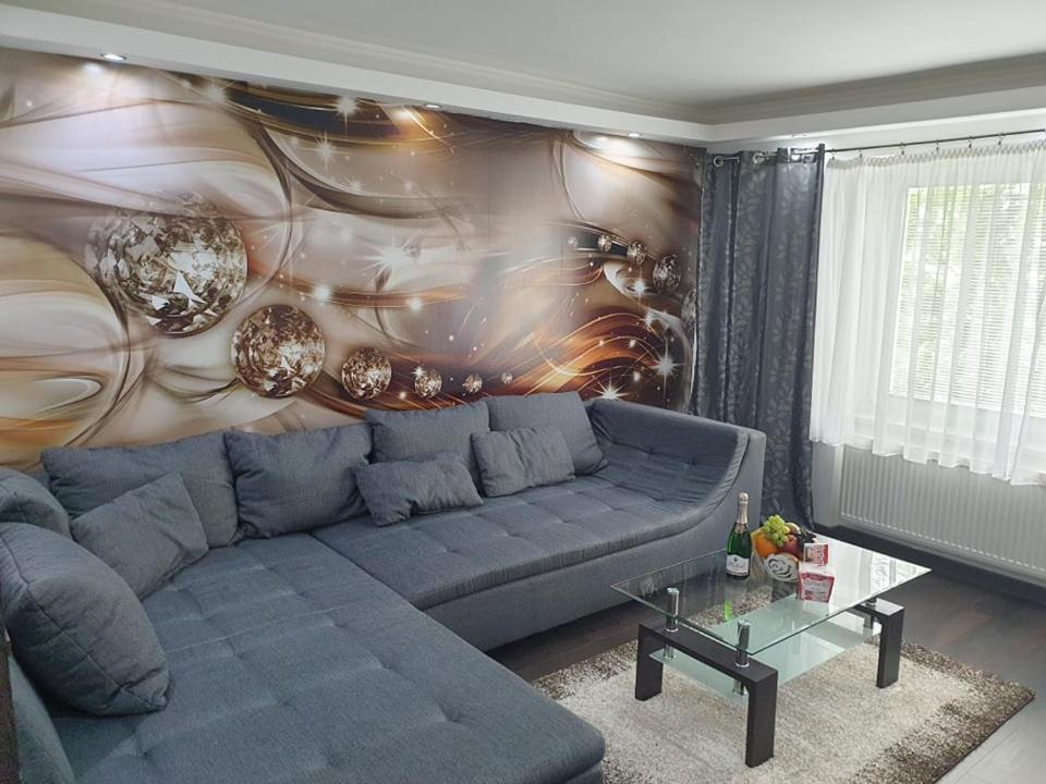 ein Wohnzimmer mit einem blauen Sofa vor einer Wand in der Unterkunft Apartmán Lana Bojnice in Bojnice
