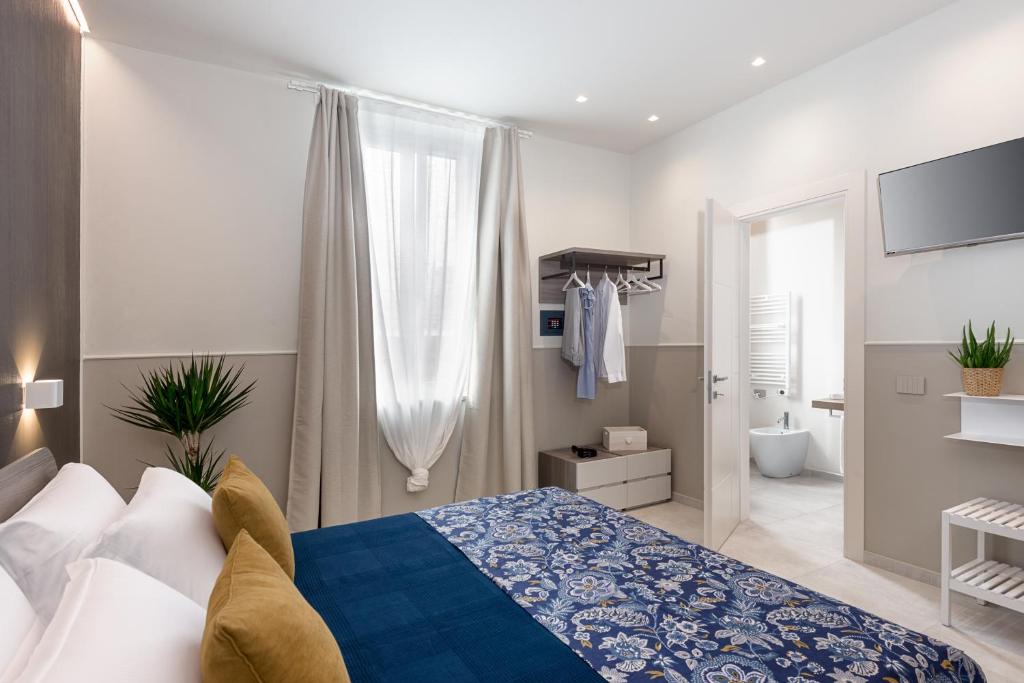 Un dormitorio con una cama azul y blanca y un baño. en Oltremare en Follonica