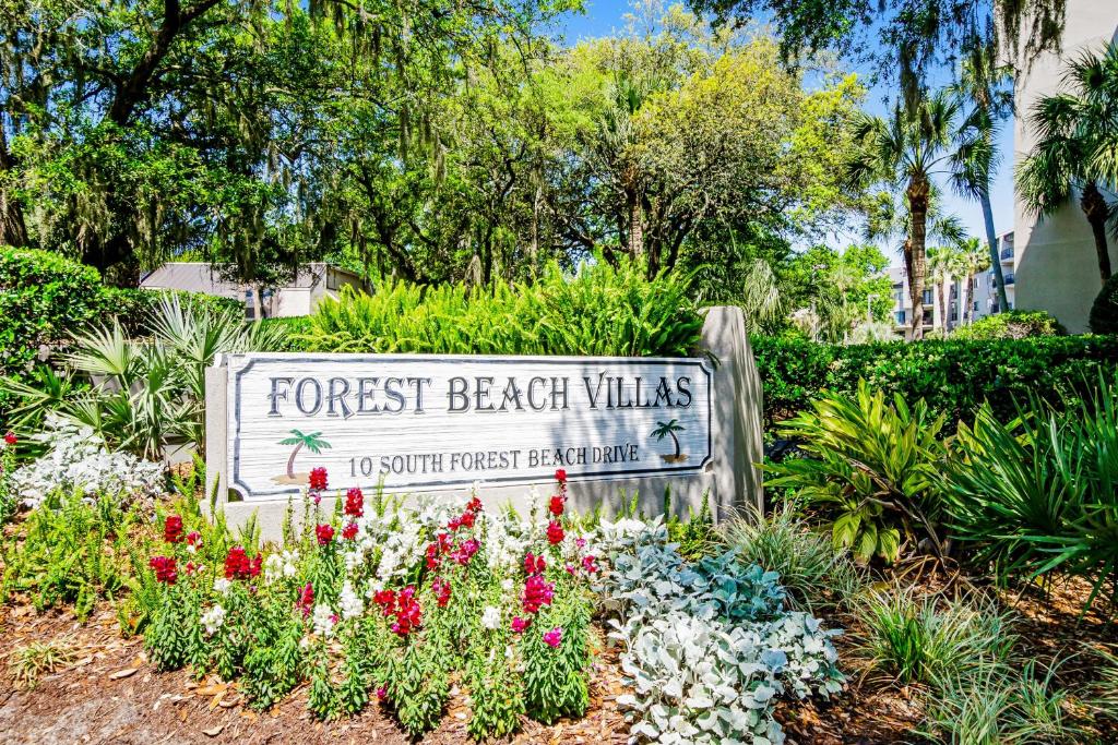 a sign for the forest beach villas with flowers at Forest Beach Villas in Hilton Head Island