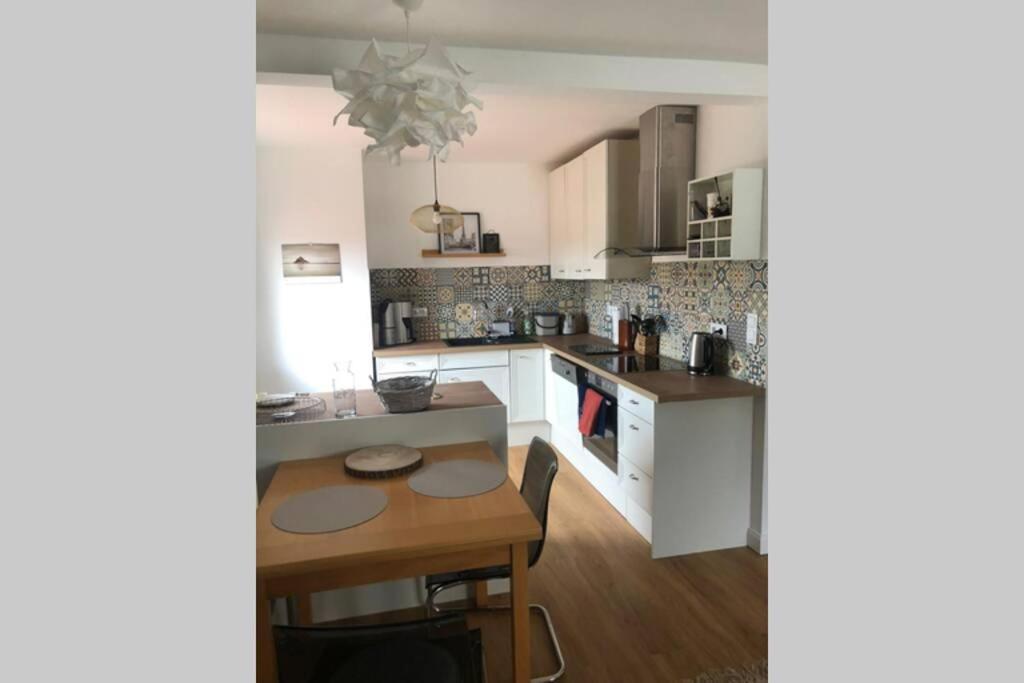 cocina con armarios blancos y mesa de madera en 5-Zi. Wohnung in Bahnhofsnähe - 24/7 self-check-in en Borstel