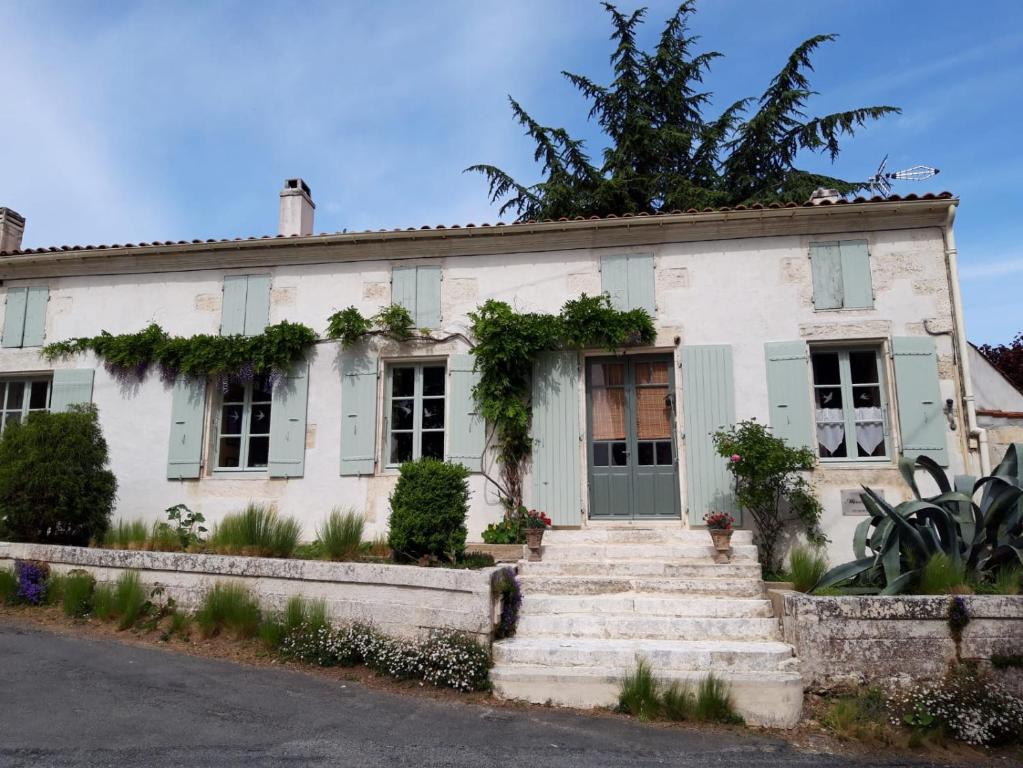 Biały dom ze schodami przed nim w obiekcie Maison Lépie w mieście Beurlay