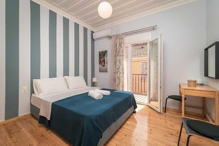 a bedroom with a bed with blue sheets and a window at Sivylla Apartments in Lefkada