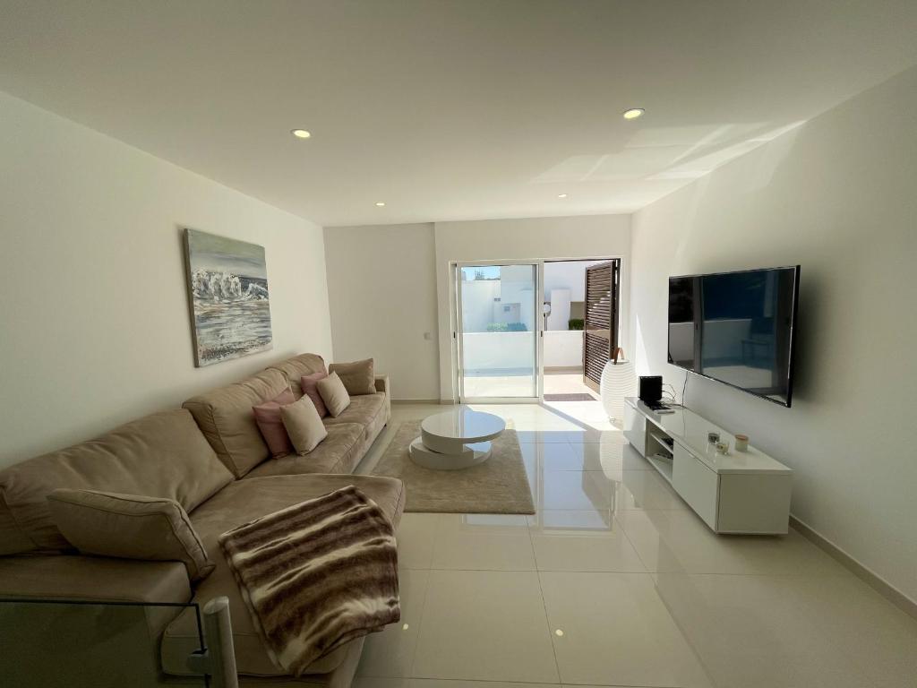 a living room with a couch and a flat screen tv at Casa Rosa - Vilamoura in Vilamoura