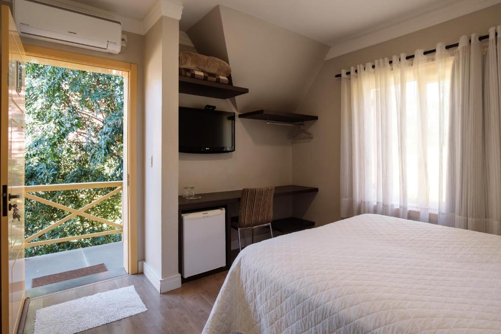 um quarto com uma cama e uma grande janela em Pousada Do Chalé em Bento Gonçalves