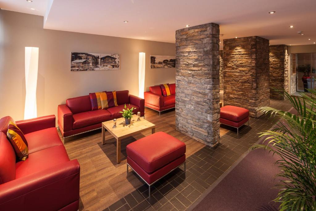a waiting room with red furniture and a stone pillar at Alpine Hotel Perren in Zermatt
