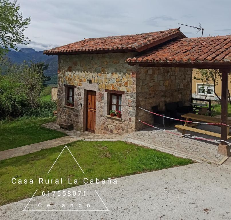 une petite maison en pierre avec une table en face dans l'établissement Casa Rural La Cabaña, à Cangas de Onís