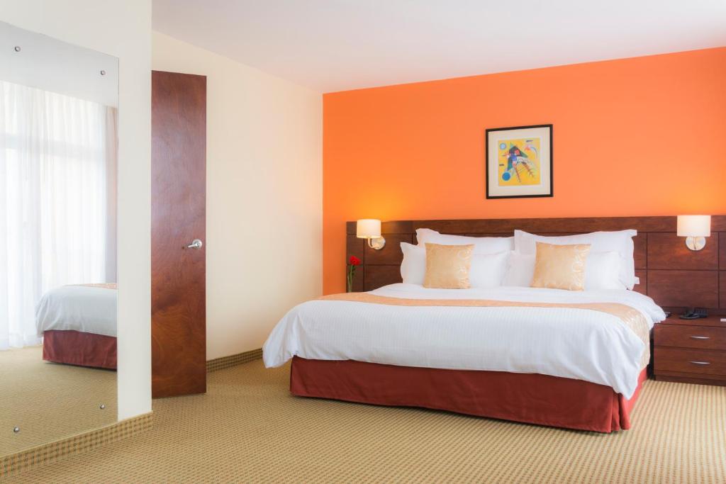 a hotel room with two beds and an orange wall at CONTINENTAL ALTAMIRA in Caracas