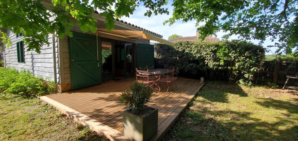 una terraza de madera con una mesa y una silla. en Gite 4kms plage grand domaine privé lacs natura 2000 en Lit-et-Mixe