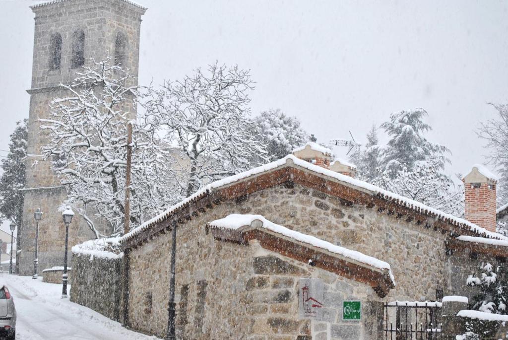 un edificio cubierto de nieve frente a una iglesia en El Patio de Valentina, en Navacerrada