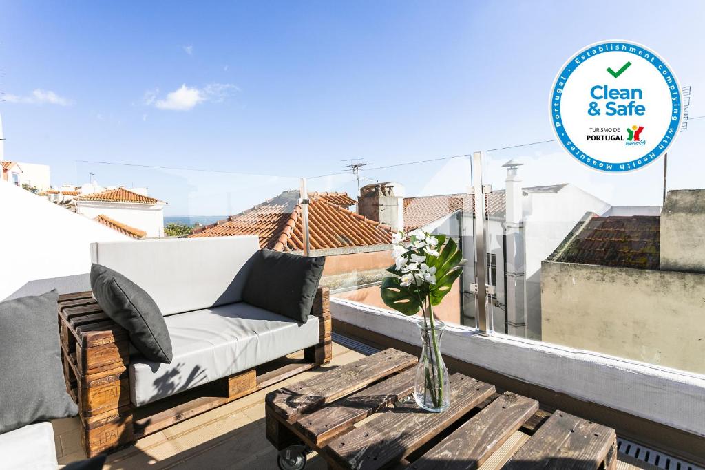 einen Balkon mit einem Sofa und einem Tisch auf dem Dach in der Unterkunft Cosy Alfama Hideout - with rooftop terrace in Lissabon