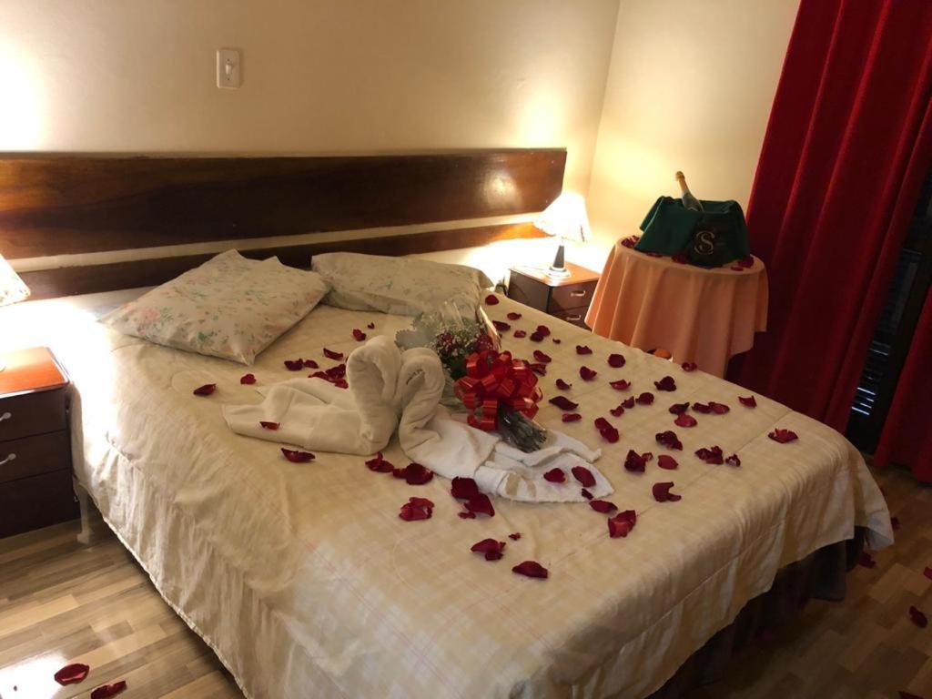 Una cama con un montón de rosas. en Pousada Palacio Monterei, en Campos do Jordão