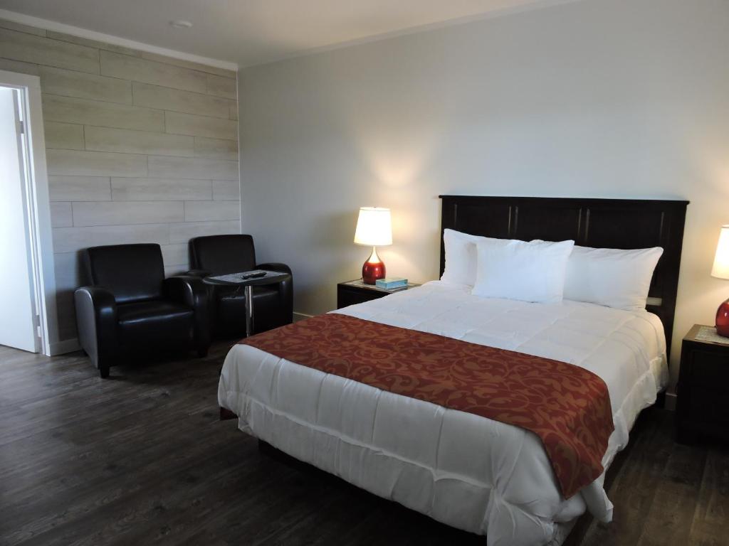 a hotel room with a large bed and two chairs at Almo Court Motel in Cranbrook