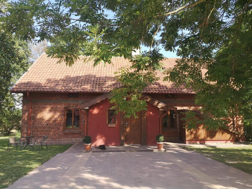 a red house with a cat sitting in front of it at Gospodarstwo Agroturystyczne "Dom na kolonii" in Prostki