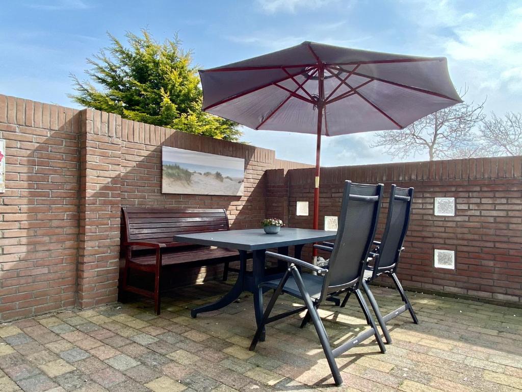 einen Tisch und Stühle mit einem Regenschirm und einer Bank in der Unterkunft Reumann Holiday Apartments: De Schelp in Zandvoort