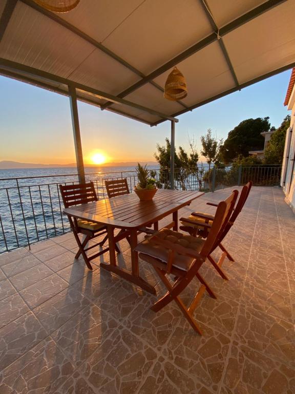 a wooden table and chairs on a patio with the sunset at Sea House Kitries in Kitriaí