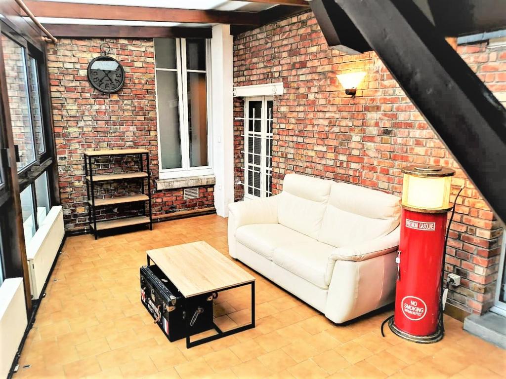 uma sala de estar com um sofá branco e uma parede de tijolos em Greyhound - Grand Appartement centre-ville em Soissons