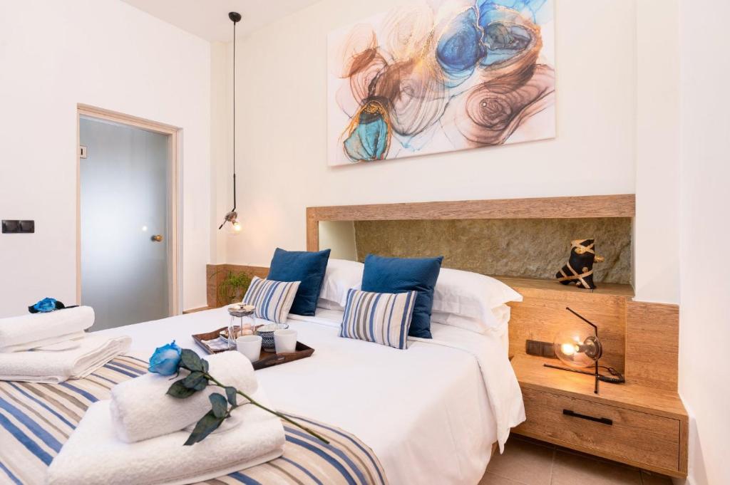 um quarto com uma grande cama branca com toques azuis em MATALA * LUX CAVE em Matala