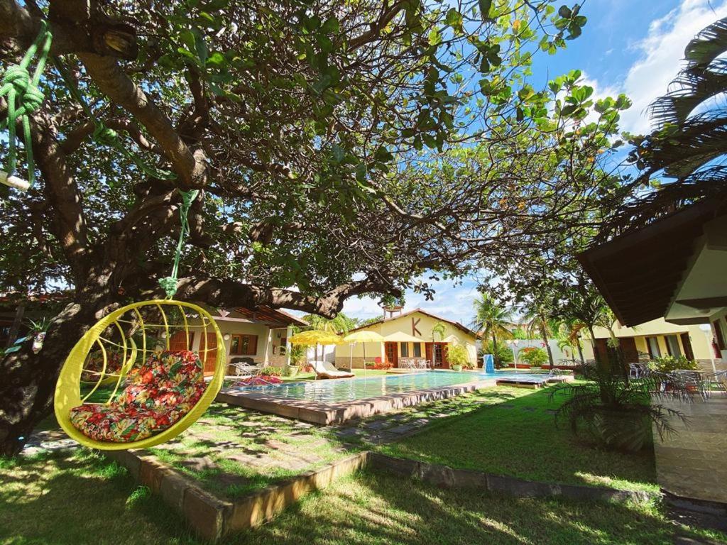 uma roda amarela pendurada numa árvore num quintal em Paracuru Kitefriends Lux Pousada em Paracuru