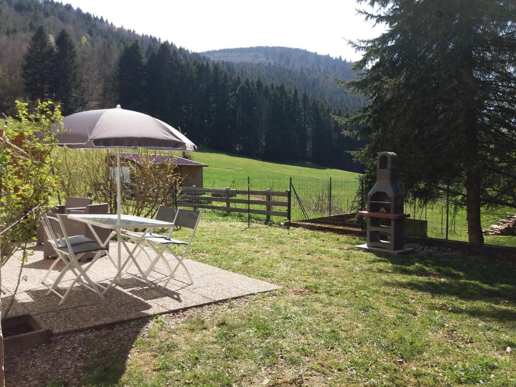 a table and chairs with an umbrella and a wood stove at Appartement 4 personnes tout équipé VOSGES. in Rochesson