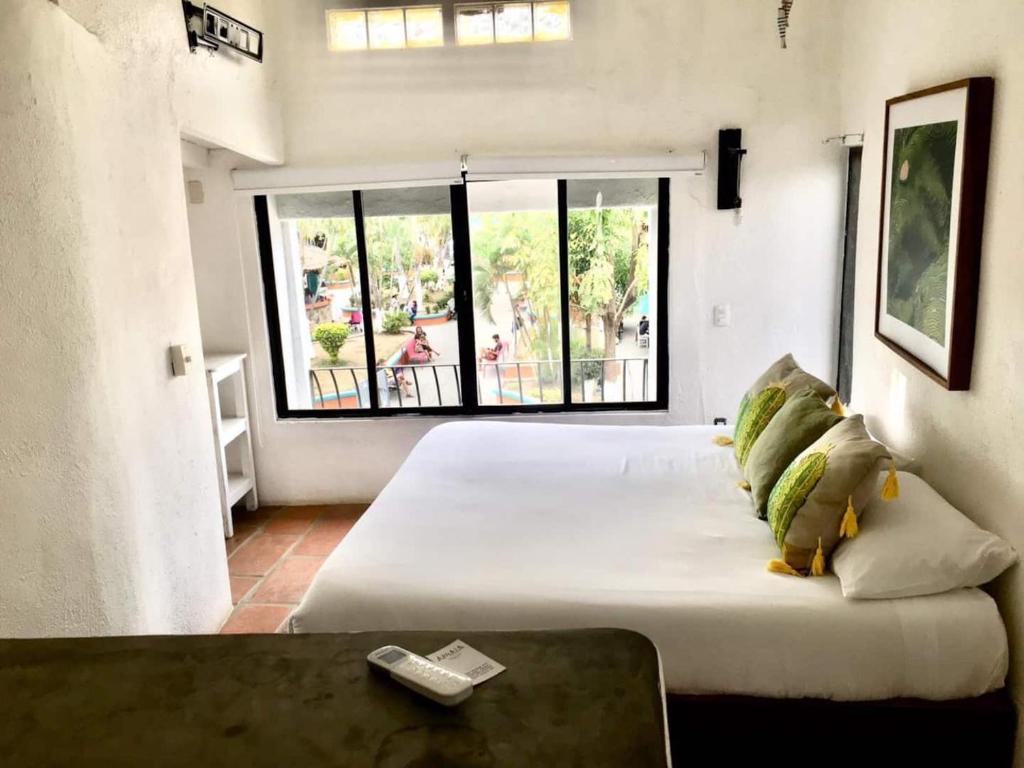 a large bed in a room with a large window at Estudio sobre calle principal con vista a la plaza in Sayulita