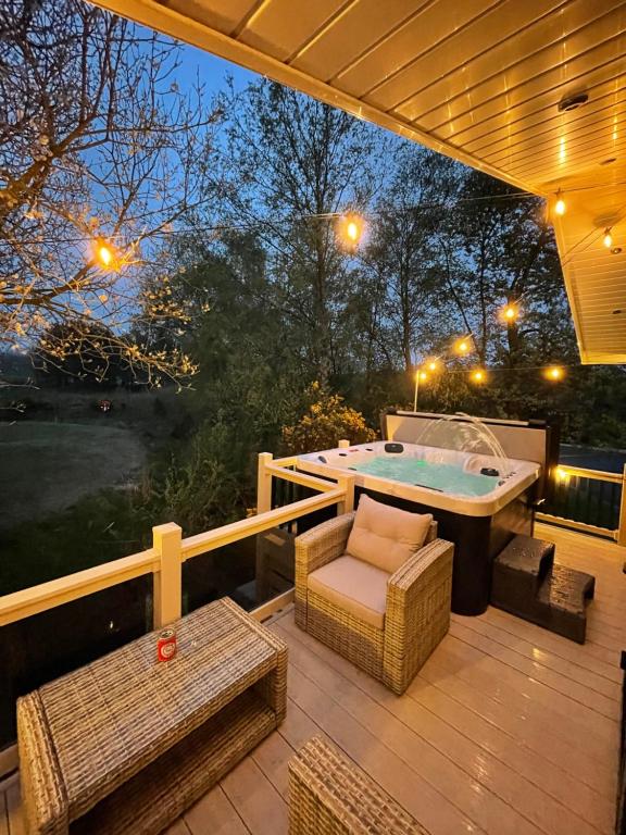um deque com uma banheira de hidromassagem, uma mesa e cadeiras em Torrey Pines - 2 bedroom hot tub lodge with free golf, NO BUGGY em Swarland