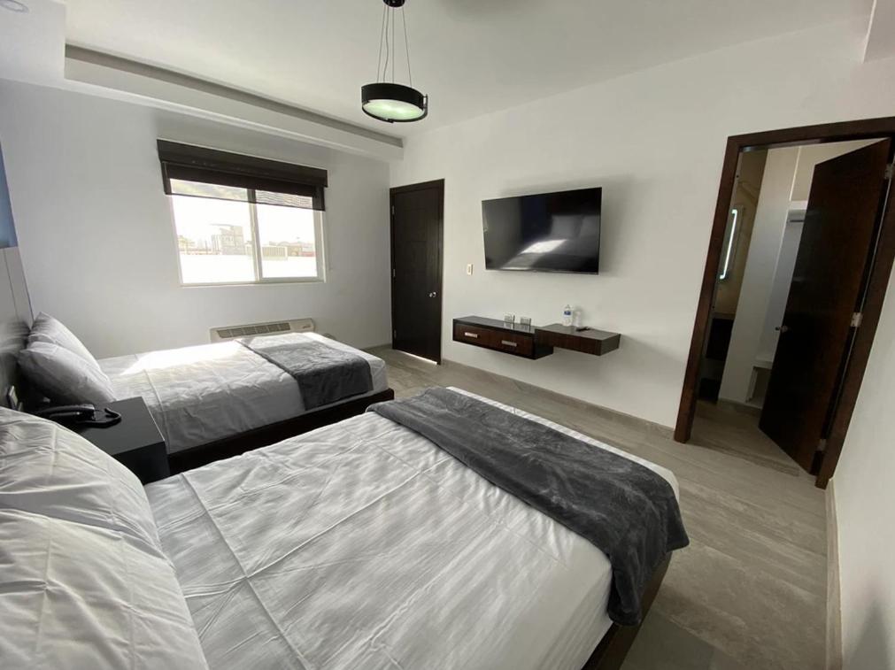 a hotel room with two beds and a television at SAND MAR HOTEL in Puerto Peñasco